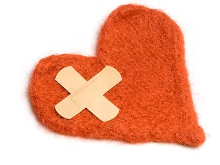 A red fabric heart repaired with two crossed plasters